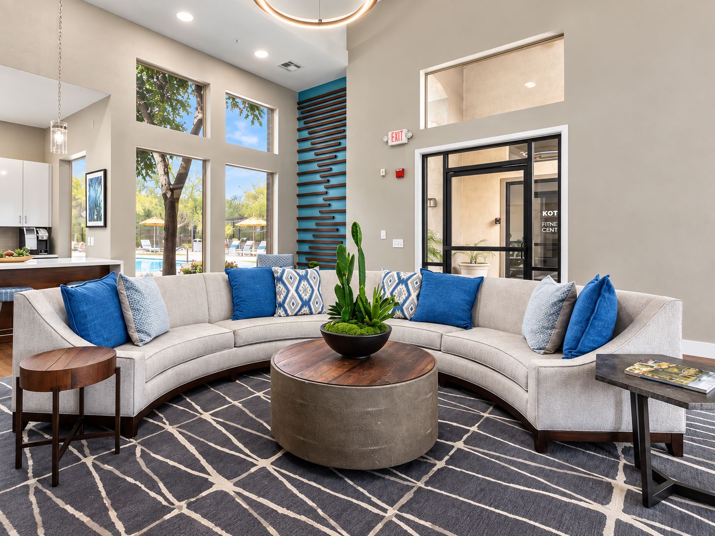 A modern lobby with a curved sofa, a round coffee table, and a patterned rug.