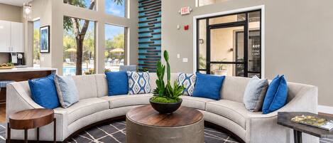 A modern lobby with a curved sofa, a round coffee table, and a patterned rug.