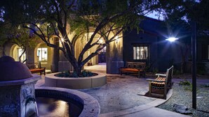 A courtyard with a fountain, benches, and a building with arches. - Meridian CondoResorts (Scottsdale)