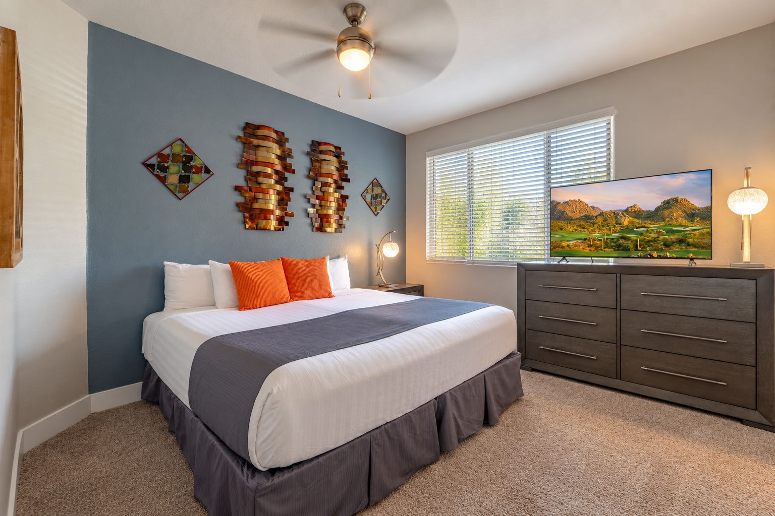 A bedroom with a bed, a dresser, a television, and artwork on the wall.
