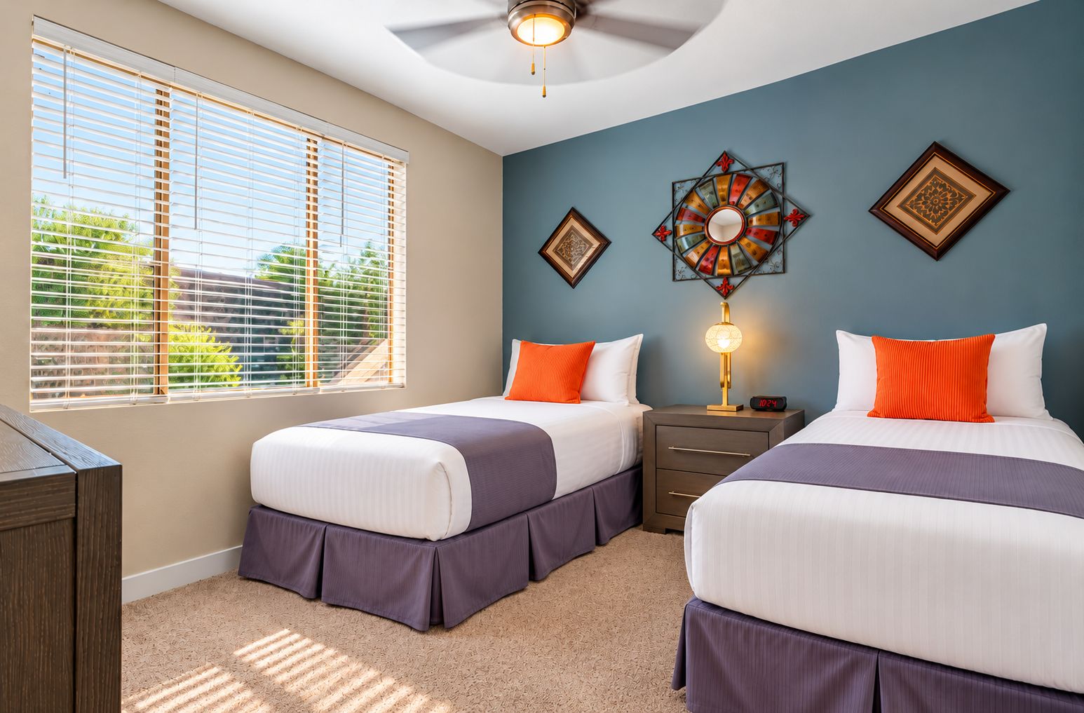 A hotel room with two beds, a nightstand, a lamp, and decorative wall art.