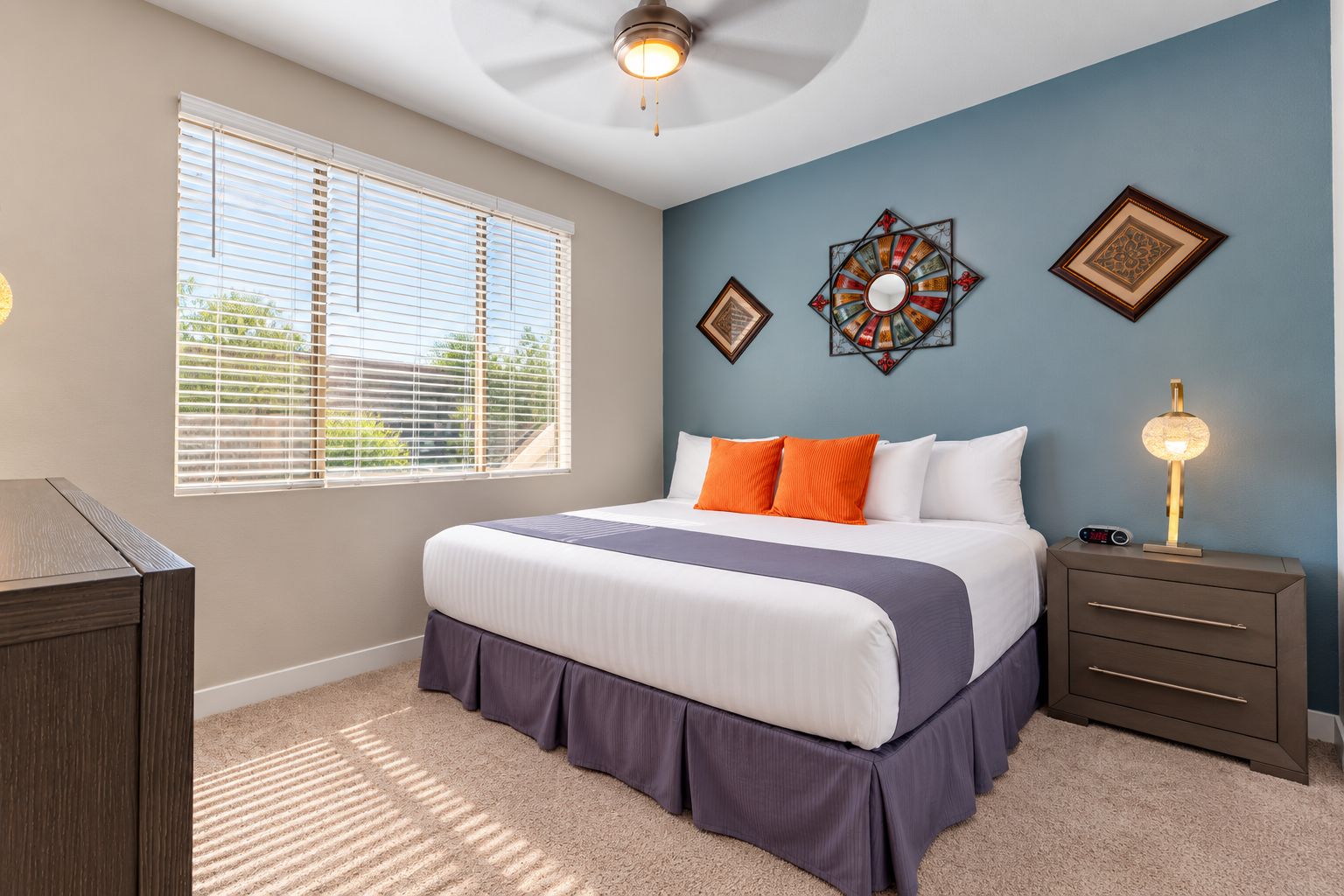 A bedroom with a bed, nightstand, and wall decor.