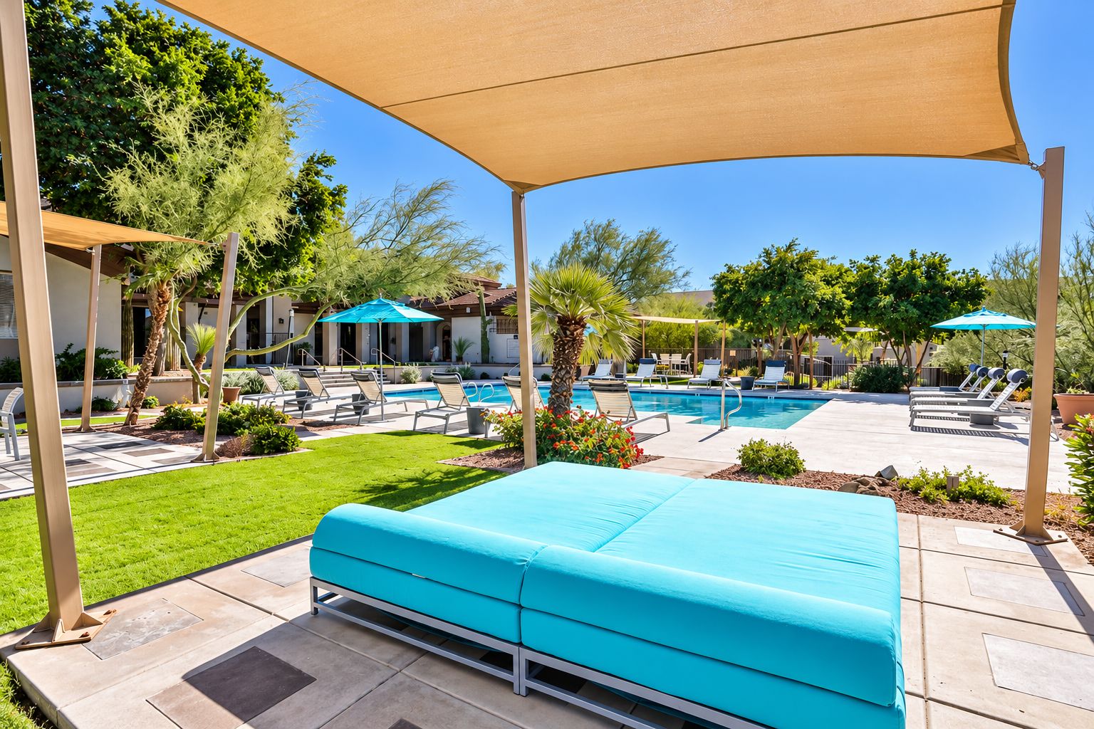 A poolside area with a blue sofa, lounge chairs, and umbrellas.