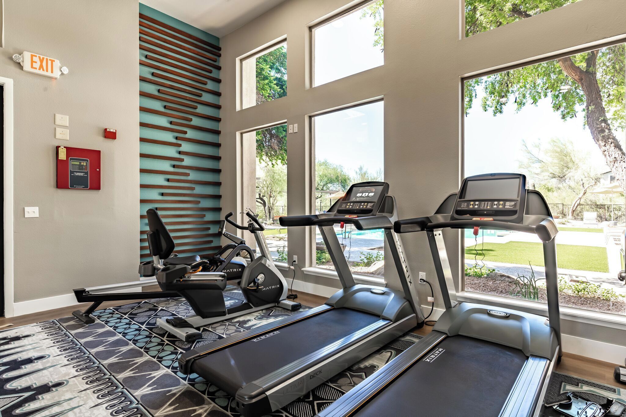 A fitness room with treadmills, a stationary bike, and a wall-mounted exercise machine.