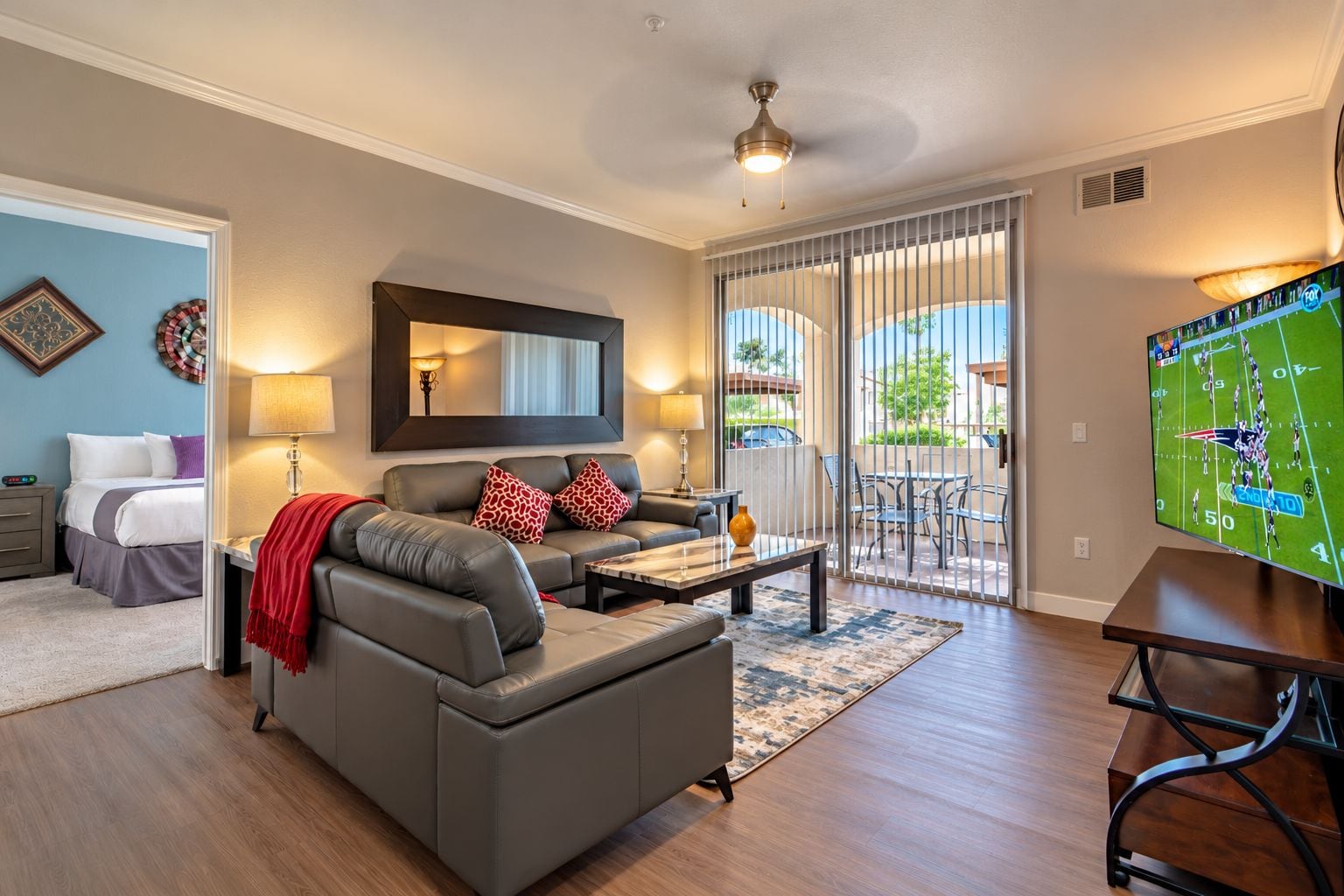 A modern living room with a sofa, coffee table, and a television displaying a sports game.