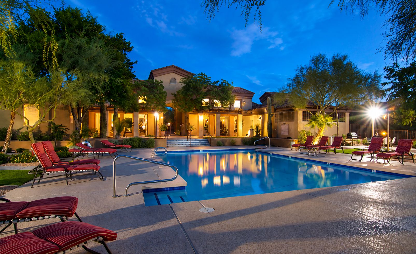 A swimming pool with lounge chairs and a building in the background.