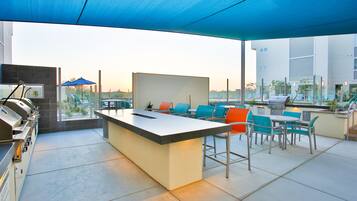 An outdoor patio with a grill station, seating area, and a view of the cityscape.