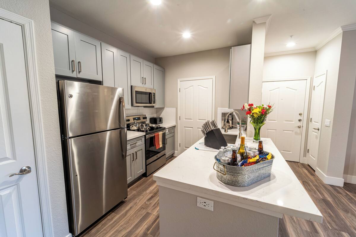 A modern kitchen with stainless steel appliances, a central island, and a white countertop.
