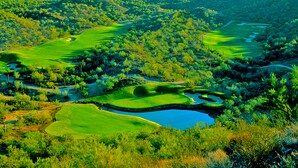 A golf course with multiple greens, water hazards, and a mountainous backdrop. - Meridian CondoResorts (Scottsdale)