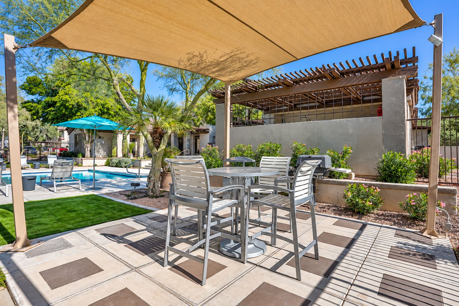 An outdoor patio area with a pool, lounge chairs, and a barbecue grill.