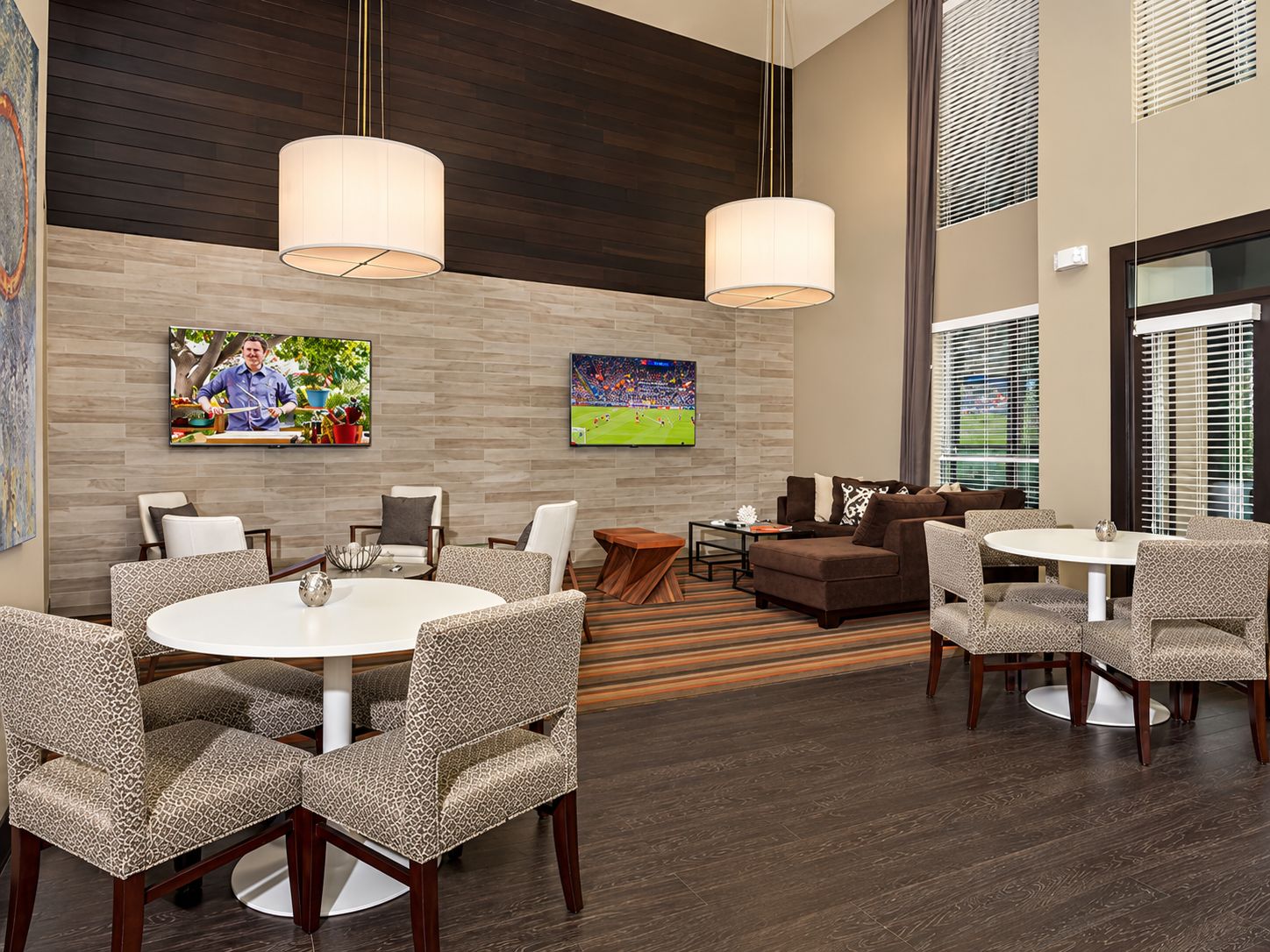 A modern hotel lobby with a dining area, sofas, and two large pendant lights.