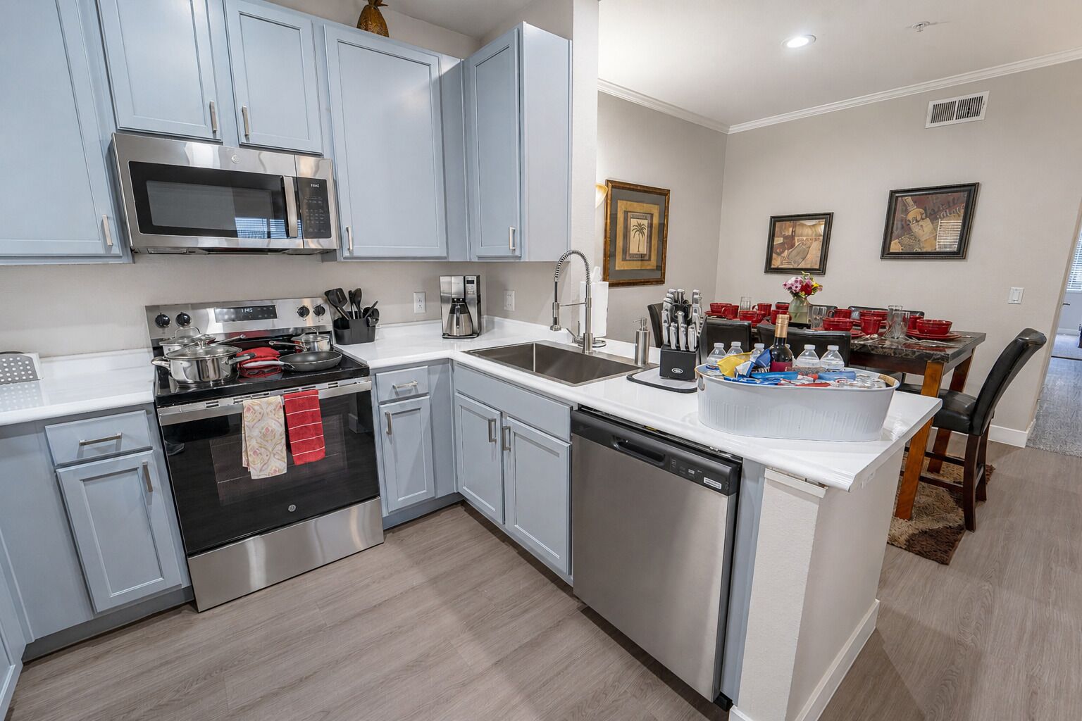 A modern kitchen with stainless steel appliances, a dishwasher, and a dining area with a table set for four.