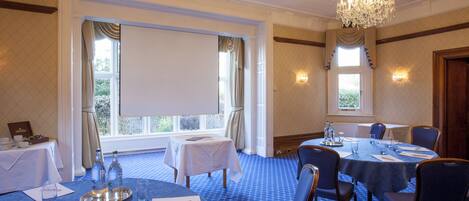 A conference room with a large table, chairs, a chandelier, and a projector screen.