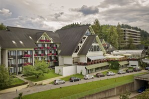 Hotel features a modern design with balconies, outdoor seating areas, and a well-manicured lawn.