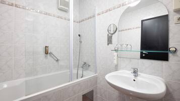 Une salle de bain moderne avec une douche à parois de verre, un lavabo blanc et un miroir au-dessus du lavabo.