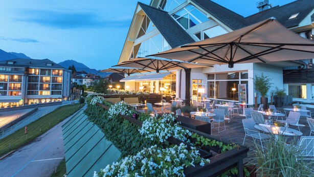 A modern building with a patio area featuring outdoor seating and a large umbrella.