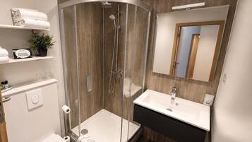 Une salle de bain moderne avec une douche à parois de verre, un lavabo blanc et des toilettes.