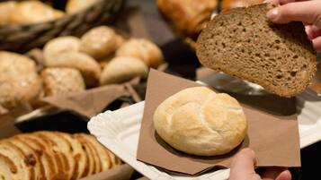 Une variété de pains et de viennoiseries sont exposés, dont un pain que tient une personne.
