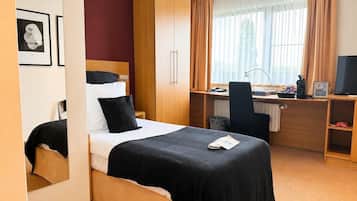 A hotel room with a bed, a desk, a chair, and a television.