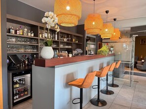 A bar area with shelves of liquor bottles, a cash register, and bar stools. - Axis Hotel (Kortenberg)