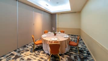Un salón de conferencias con una mesa redonda, sillas anaranjadas y una lámpara en el techo.