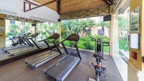 Un gimnasio con cintas de correr, una bicicleta estática y una máquina de pesas.