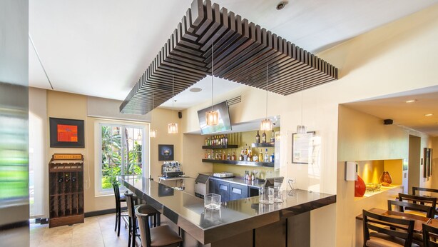 Una cocina moderna con una isla grande, taburetes de bar y una estantería para vinos.