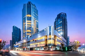 A modern building with multiple floors, large windows, and a curved facade. - Shanghai QILU Hotel (Shanghai)
