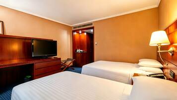 Une chambre d’hôtel avec deux lits, une télévision, un bureau, une lampe et une armoire.