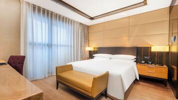 Une chambre d’hôtel avec un grand lit, un bureau, une chaise et une table de chevet avec une lampe.