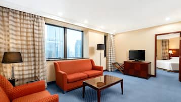 Une chambre d’hôtel avec une grande fenêtre, un canapé, une table basse, une télévision et un lit.