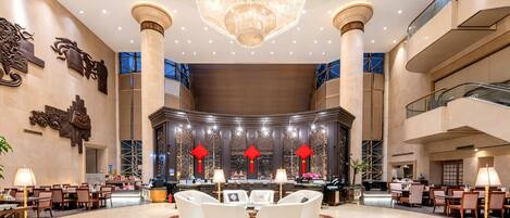 A spacious lobby with a chandelier, seating areas, and a reception desk.