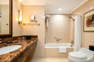 A bathroom with a marble sink, a bathtub, a toilet, a shower, and a mirror.