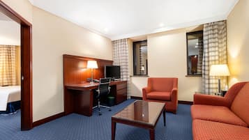 Habitación de hotel con cama, escritorio con computadora, silla, sofá y televisión.