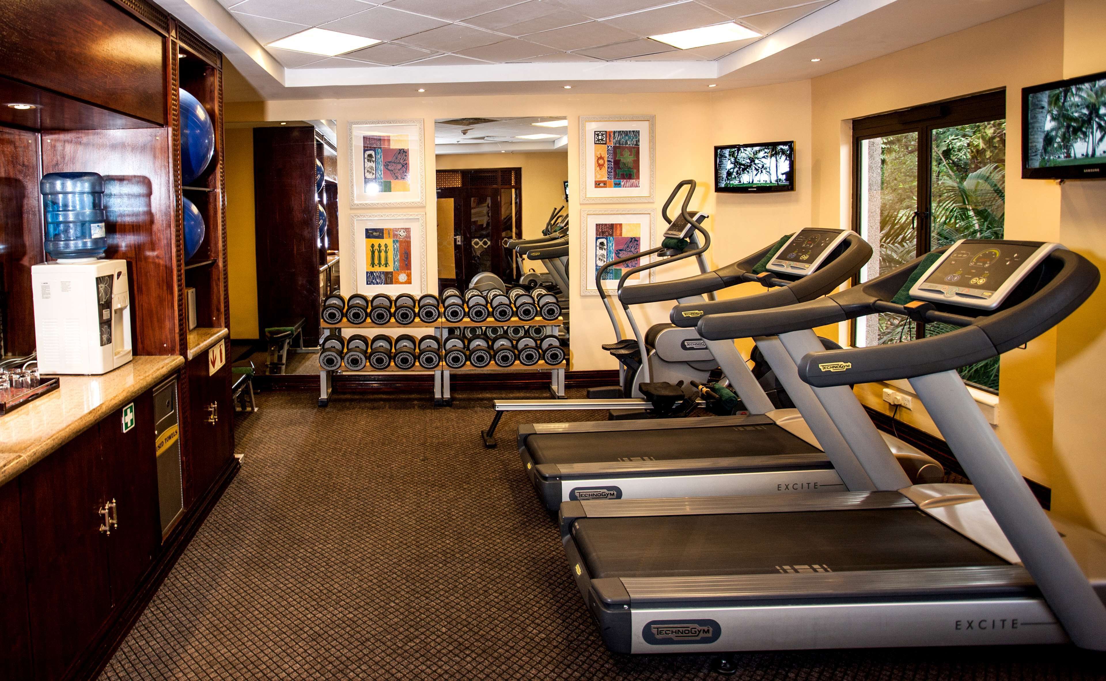 A gym with treadmills, dumbbells, and a water dispenser.