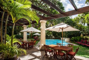 Una piscina al aire libre, sombrillas, tumbonas