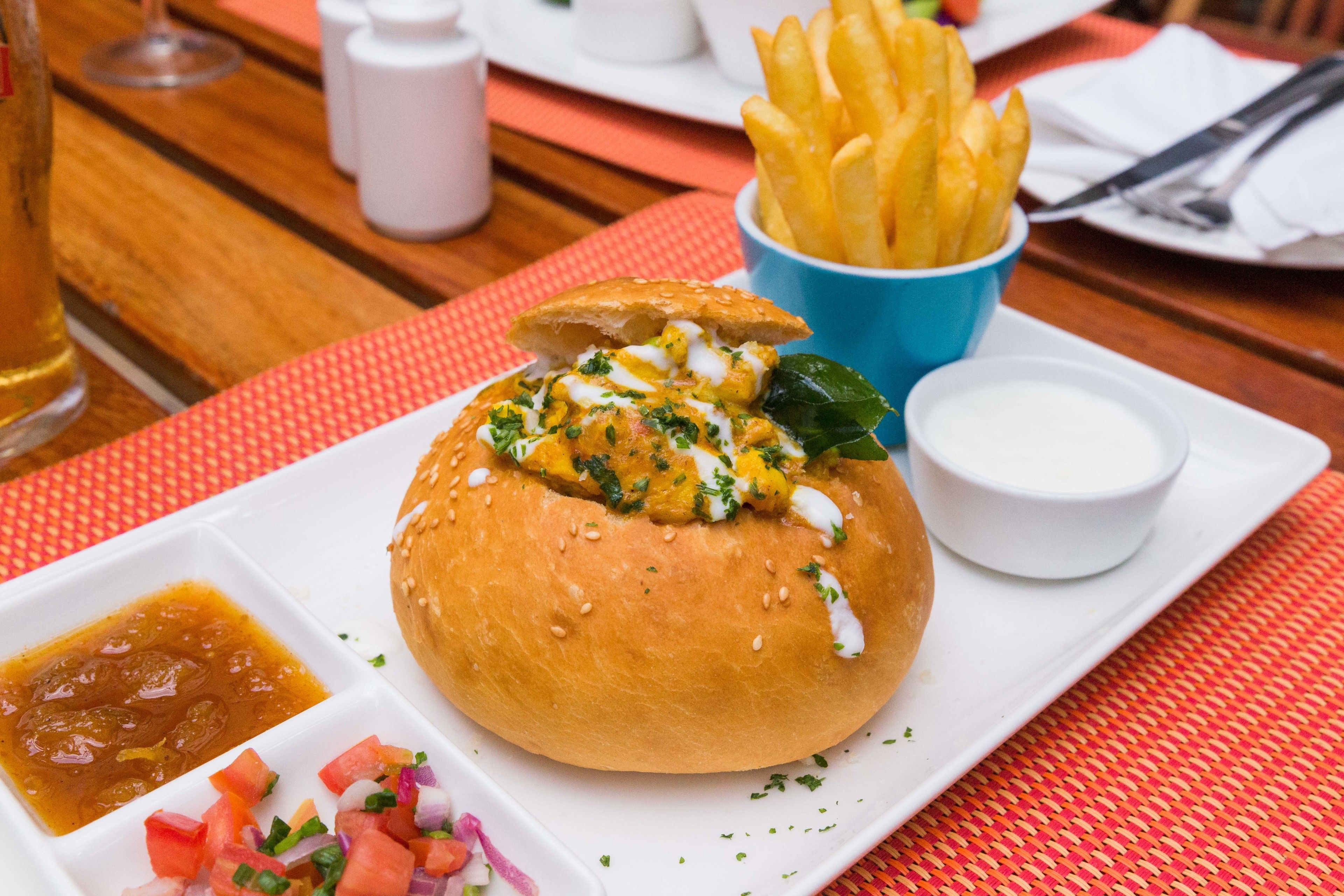 Una comida con hamburguesa, papas fritas y salsas sobre una mesa.