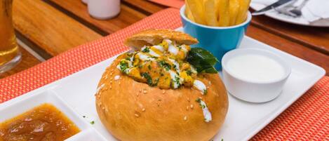 Una comida con hamburguesa, papas fritas y salsas sobre una mesa.