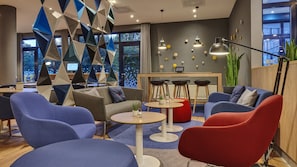 A modern lounge area with seating, tables, and a view of the outdoors.