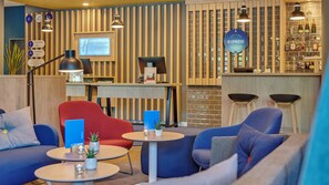 A hotel lobby with seating, a reception desk, and a bar area.
