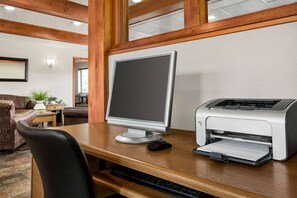 A wooden desk with a desktop computer and a printer in a room with a wooden ceiling and a couch. - Baymont by Wyndham Whitefish (Whitefish)