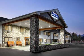 A hotel with a stone facade, multiple windows, and a covered entrance area. - Baymont by Wyndham Whitefish (Whitefish)