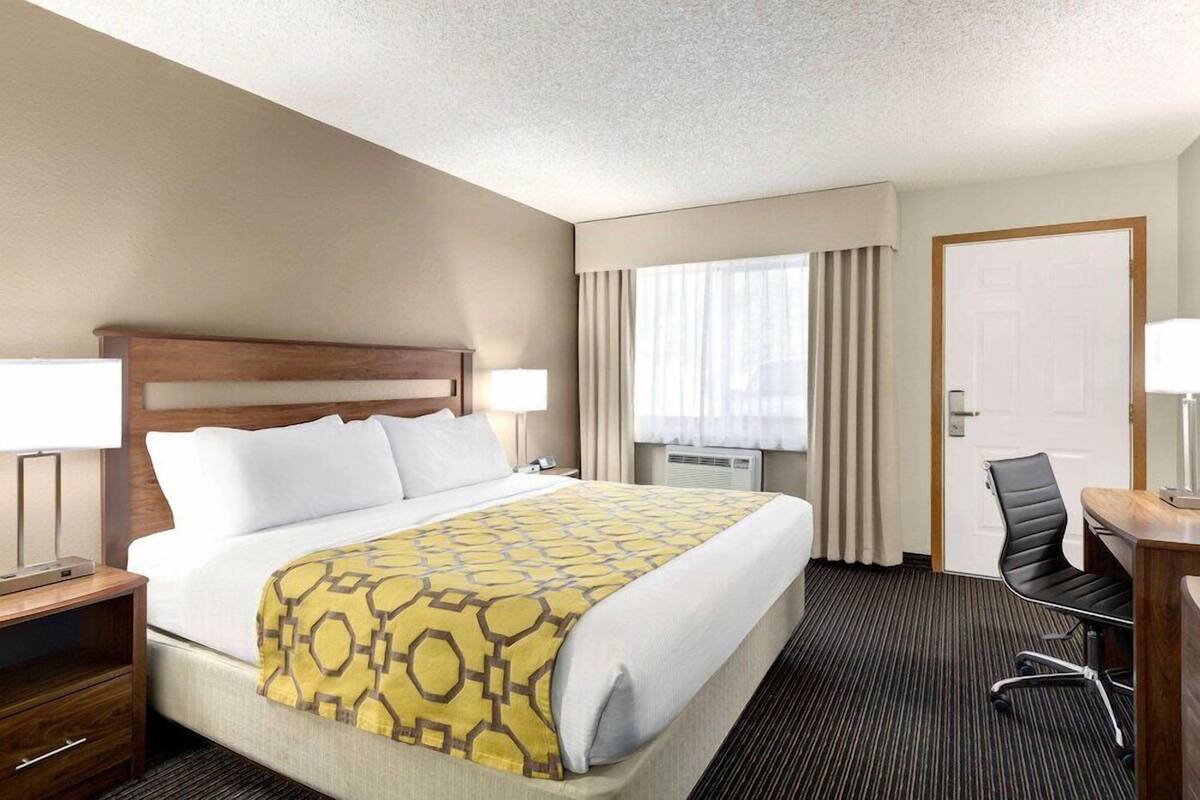 A hotel room with a bed, bedside tables, a desk, and a chair.
