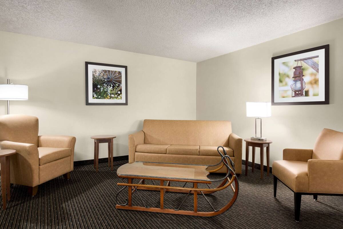 A hotel room with a sofa, armchairs, a rocking chair, a small table, and two lamps.