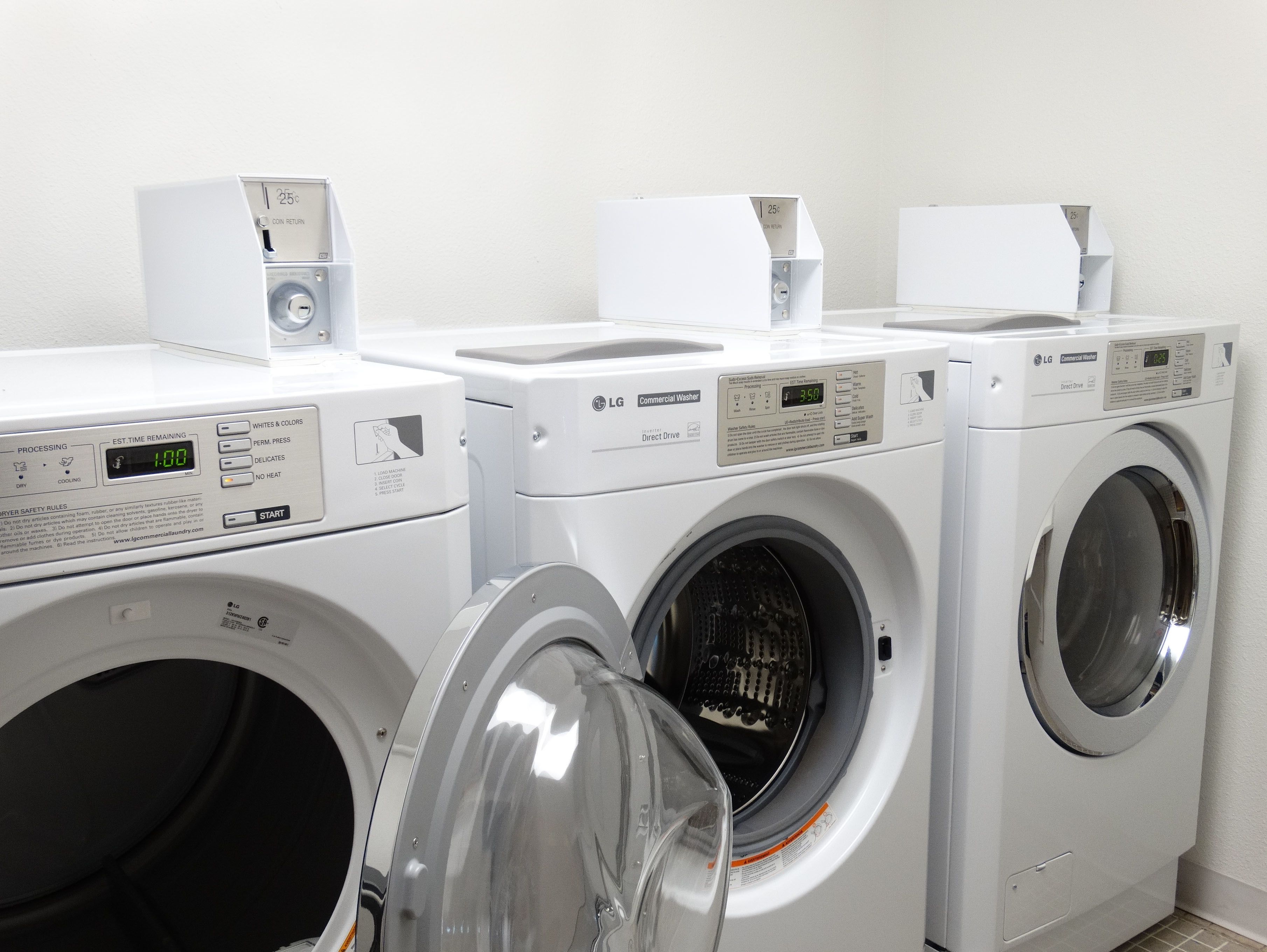 Een rij witte LG commerciële wasmachines met digitale displays en bedieningspanelen.