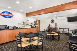 A breakfast area with a counter, chairs, and tables. - Baymont by Wyndham Whitefish (Whitefish)