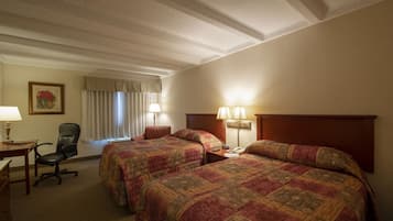 A hotel room with two beds, a desk, a chair, and a window with curtains.