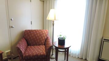 Una habitación con un sillón estampado, una pequeña mesa con una planta en maceta y una lámpara.