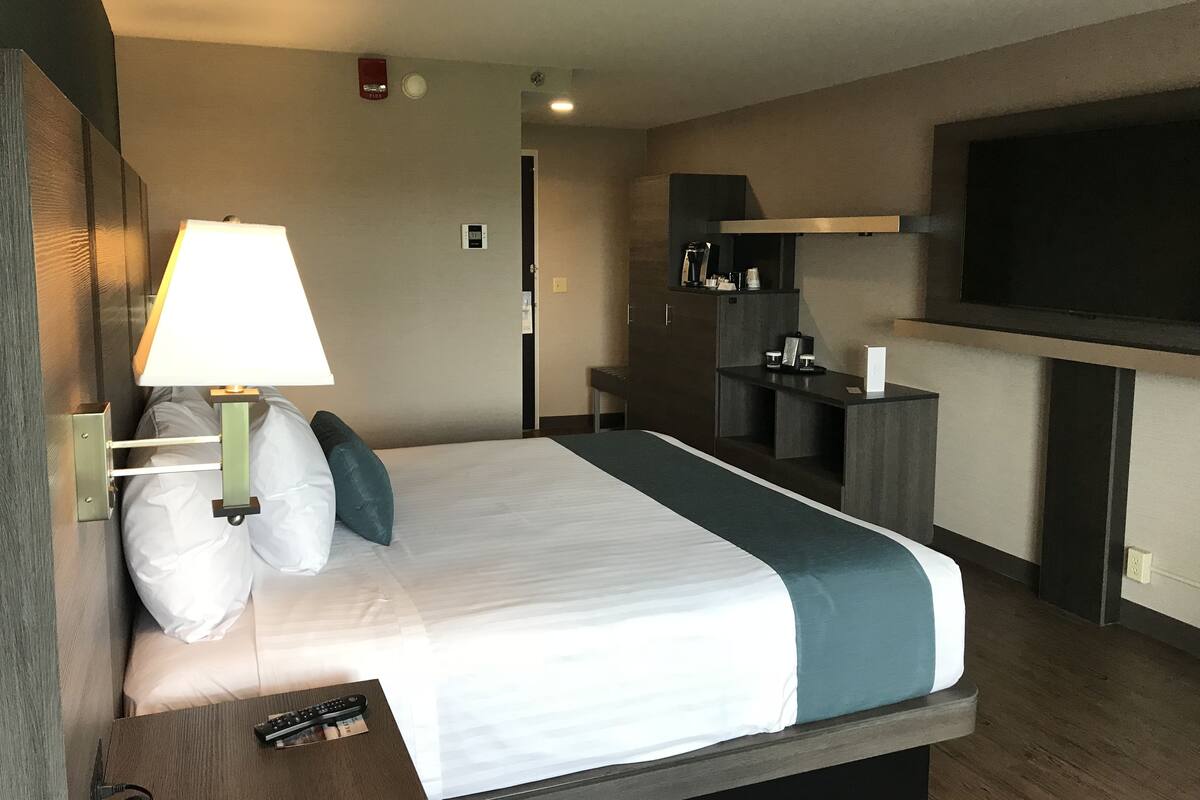 A hotel room with a bed, a TV, a desk, and a lamp.