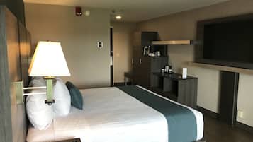 A hotel room with a bed, a TV, a desk, and a lamp.